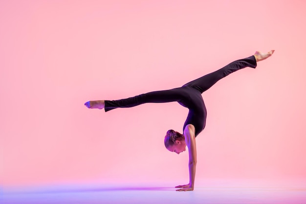 Dançarina de jovem adolescente dançando sobre um fundo vermelho do estúdio. Balé, dança, arte, modernidade, conceito de coreografia