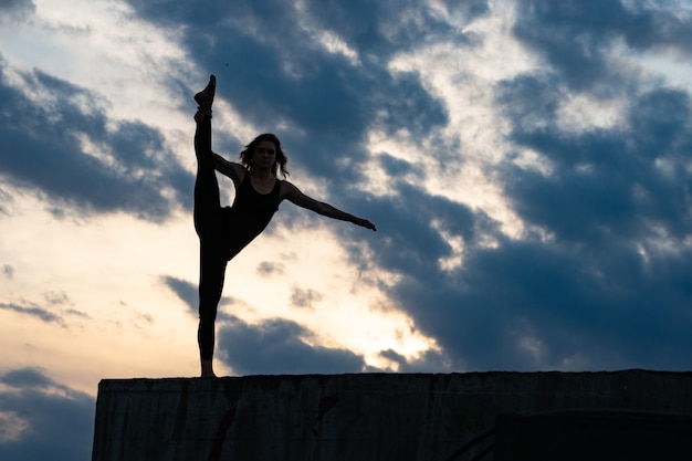 Dançarina de jovem mulher no nascer do sol ao ar livre.