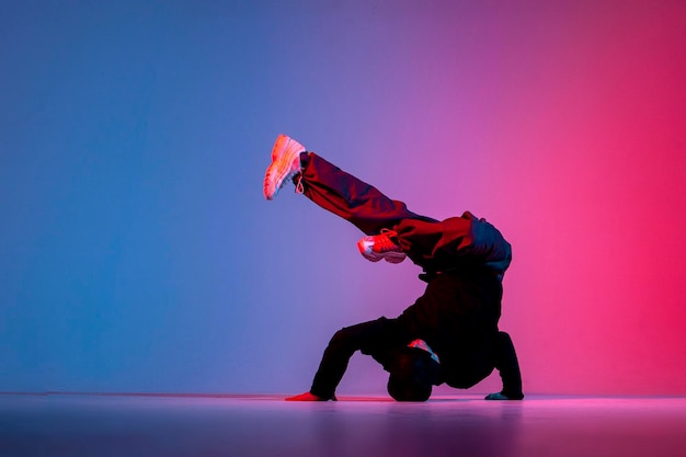 dançarina fazendo truque acrobático e dançando breakdance em iluminação vermelha e azul de néon