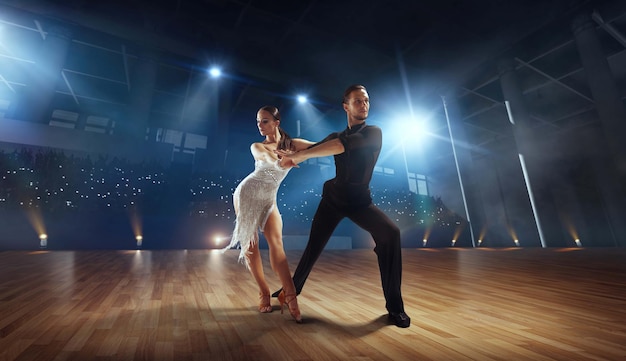 Dançarinos de casal realizam dança latina em grande palco profissional dança de salão