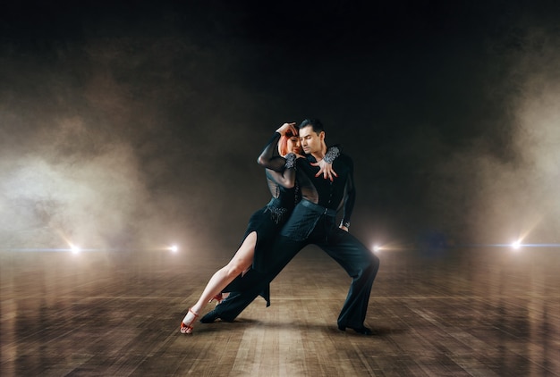 Dançarinos elegantes em trajes, dança ballrom no palco do teatro. parceiros femininos e masculinos em pares profissionais dançando na cena