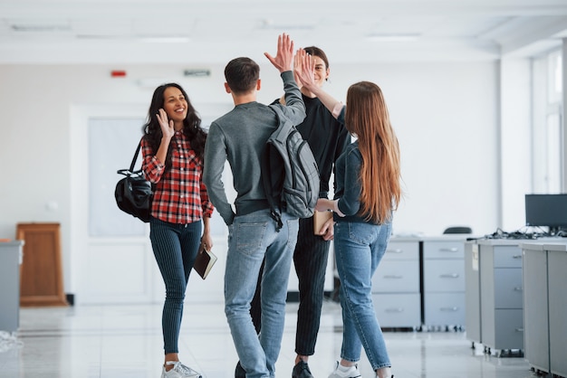 Dando mais cinco. grupo de jovens caminhando no escritório no intervalo