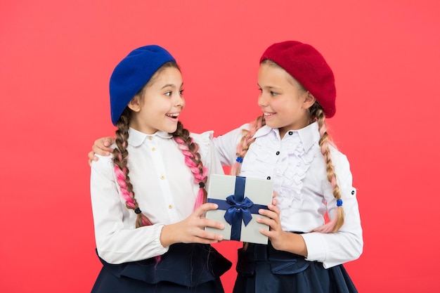 Dando el regalo para ti Linda niña pequeña dando un regalo a un amigo sobre fondo rosa Adorable niña disfruta dando el regalo a un compañero de escuela Dar y recibir van de la mano