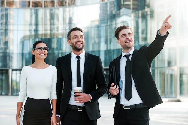 dando vida a nuevas ideas comerciales. Tres jóvenes empresarios alegres mirando a otro lado y sonriendo