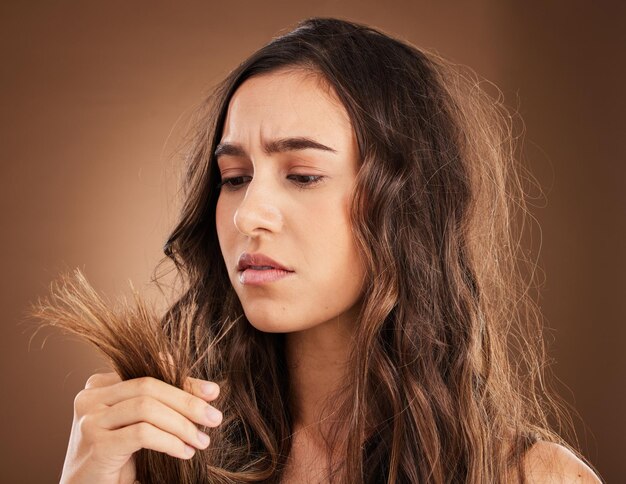 Daño en el cabello de puntas abiertas y mujer en estudio por crisis frustrada y texturas con tratamiento de salón Reparación de belleza y corte de pelo con modelo femenino sobre fondo marrón para queratina y cosmetología