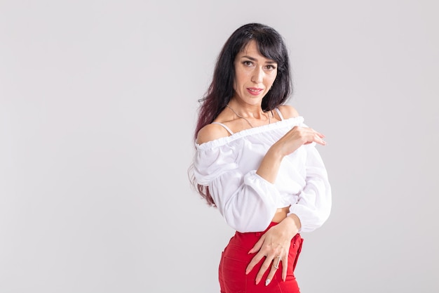 Danza latina, strip dance, concepto de dama contemporánea y bachata - Mujer bailando improvisación y moviendo su cabello largo sobre un fondo blanco con espacio de copia