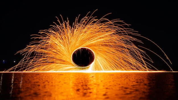 Danza nocturna del fuego. Chispas de lana de acero sobre un fondo negro. De cerca.