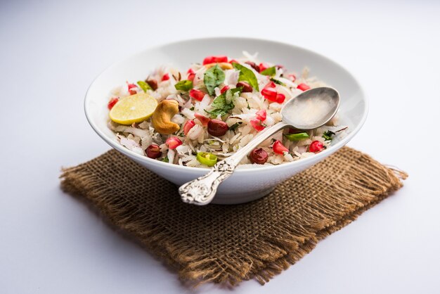 Dapde Pohe ist ein typisches Maharashtrian-Frühstück, das mit einer dünnen Auswahl an Poha und frischer Kokosnuss mit Chili, Erdnüssen und Nüssen zubereitet wird. in einer Schüssel oder einem Teller serviert. selektiver Fokus