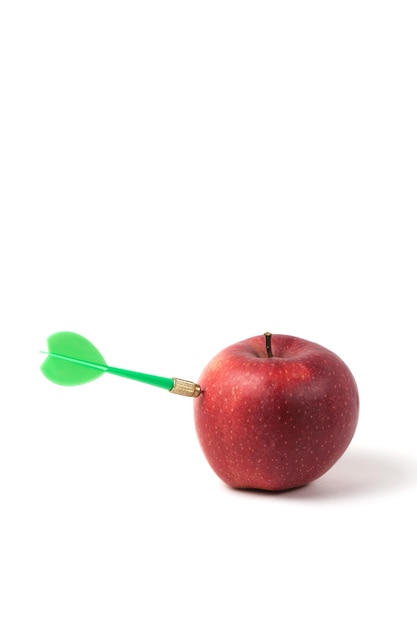 El dardo verde para jugar a los dardos golpea directamente en la manzana roja. Concepto de competencia y objetivos de logro. Alcanzar objetivos en los negocios y en la vida.