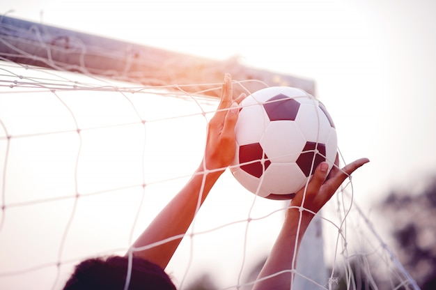 Das abgeschnittene bild von sportlern, die den ball und den fußballplatz fangen.