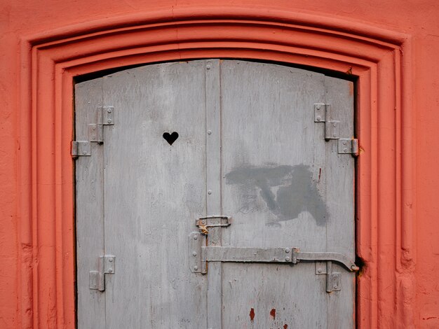 Das alte Fenster ist rosa mit Mustern. Die Herzform ist in das Fenster geschnitzt