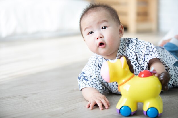 Das asiatische Baby, das horse spielt, spielt auf dem Boden