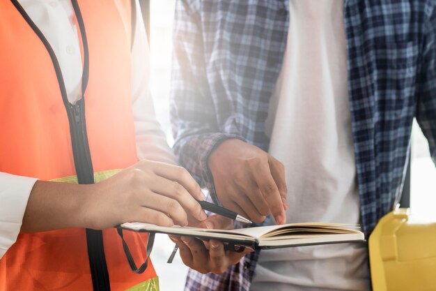 Foto das asiatische junge bauunternehmerteam, das masken trägt, während es die rekonstruierte konstruktion inspiziert und renoviert oder defekt ist, überprüft das finish, bevor es an den kunden auf der baustelle übergeben wird.