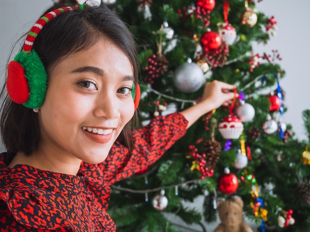 Das asiatische Mädchen, das Weihnachten im Haus feiert, Frau verzieren den Weihnachtsbaum