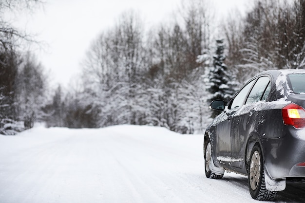 Foto das auto steht an einem bewölkten wintertag auf einer schneebedeckten straße