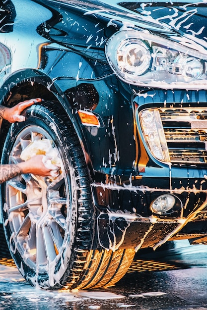 Foto das auto waschen. waschen eines schwarzen autos bei einer autowäsche. sauberes auto