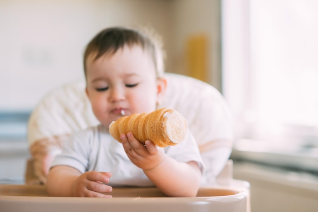 Das Baby in der Küche frisst gierig leckere cremige Tuben gefüllt mit Vanillecreme