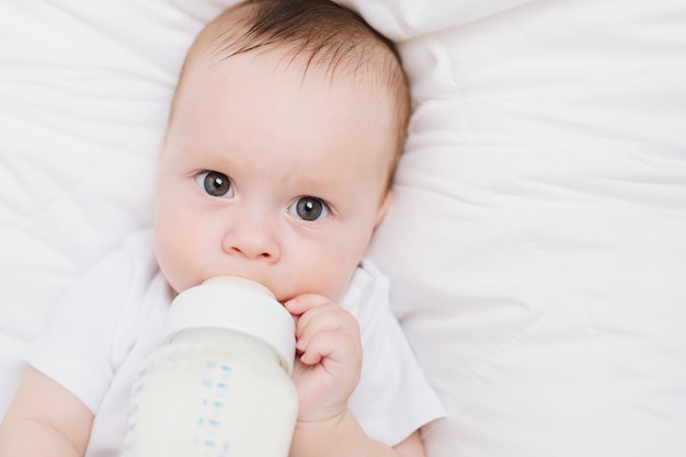 Das Baby in seiner Krippe isst aus einer Flasche Babynahrung copyspace Künstliche Fütterung