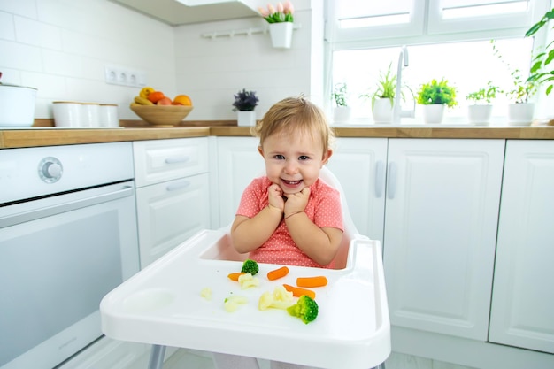 Das Baby isst Gemüse auf einem Stuhl Selektiver Fokus