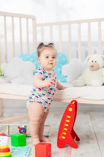 Das Baby lernt zu stehen oder auf den Füßen zu stehen, das Kind spielt zu Hause im Kinderzimmer