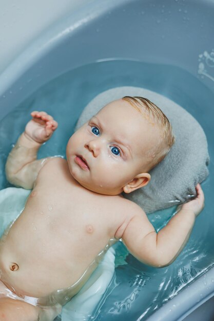 Foto das baby liegt auf einem ständer und badet in einer badewanne, ein neugeborenes in einem bad.