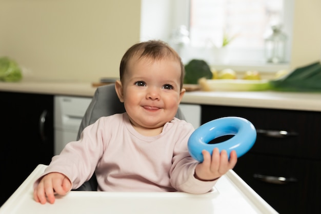 Das Baby sitzt am Kinderstuhl und wartet darauf, dass seine Mutter es füttert.