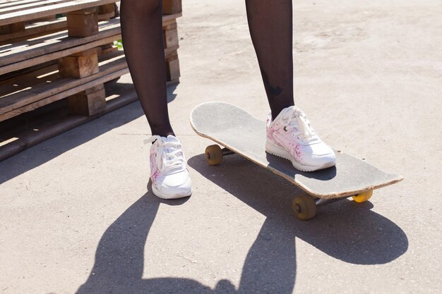 Das Bein eines Mädchens auf dem Skateboard
