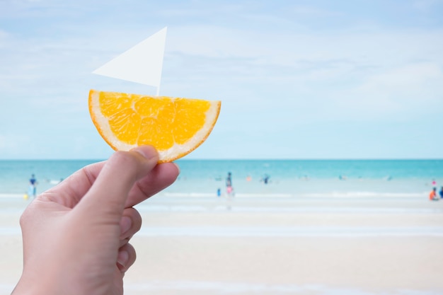 Das Bild einer weiblichen Hand, die morgens eine orange Schale auf dem Meer hält