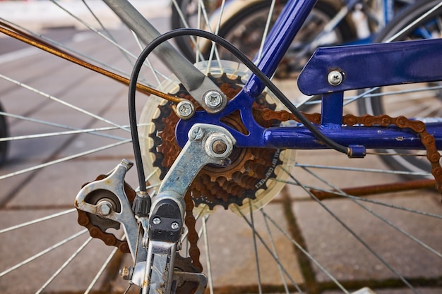 Das blaue Fahrrad war den ganzen Winter draußen und ist kaputt gegangen. Die rostige Fahrradkette hängt am Kettenrad und am Zahnrad