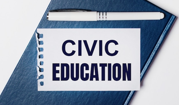 Das blaue Tagebuch liegt auf hellem Hintergrund. Auf hat einen weißen Stift und ein Blatt Papier mit dem Text CIVIC EDUCATION.