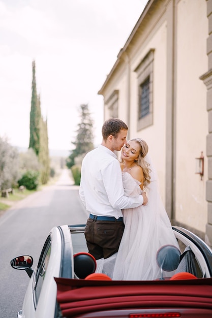 Das Brautpaar küsst sich bei einer offenen Cabrio-Hochzeit in Florenz, Italien, in einem alten Villawiner