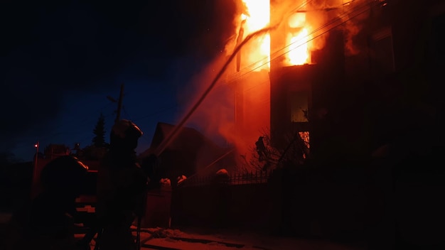 Das Dach des Hauses brennt Das Wohnhaus brennt Dorf Feuerwehrleute löschen ein Feuer vom Kran von oben Rauch und Funken