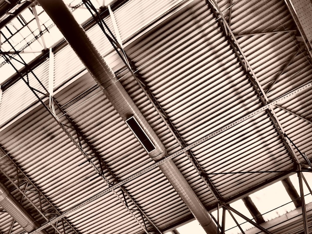 Das Dach eines Hangars, einer Produktionshalle oder einer Sporthalle, Metallkonstruktionen, Träger, Stützelemente, Lüftungssysteme in großen Hallen und Räumen, Oberlichter, Industrielle Innenräume