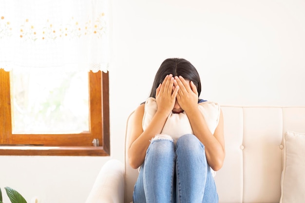 Das Depressionsmädchen sitzt auf dem Sofa und weint zu Hause