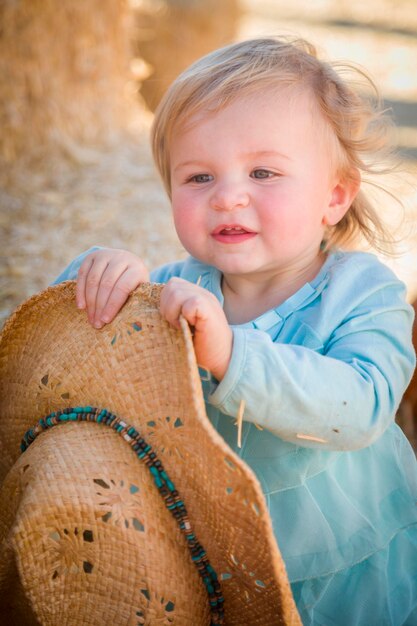 Das entzückende Baby-Mädchen mit dem Cowboy-Hut im Pumpkin PatchxA