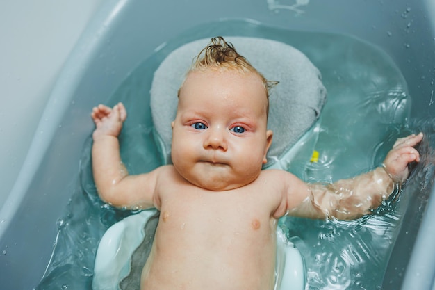 Das erste Bad des Babys Die Pflege eines Neugeborenen Das Baden eines Babys in einer Badewanne Ein Neugeborenes badet im Wasser