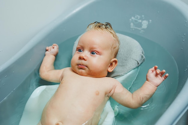 Das erste Bad des Babys Die Pflege eines Neugeborenen Das Baden eines Babys in einer Badewanne Ein Neugeborenes badet im Wasser