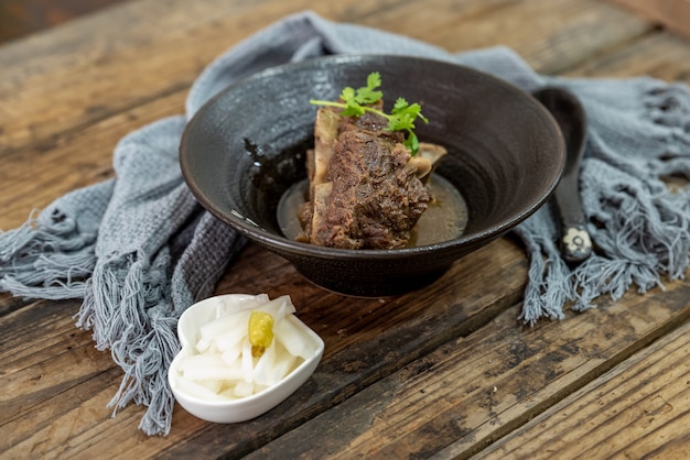 Das Essen aus Rindfleisch liegt in der Schüssel auf dem Tuch des Holztisches