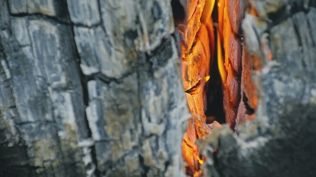 Das Feuer in Löchern mit Holz. Der Lagerfeuerriss in schwedischer oder finnischer Holzkerze. Feuer brennt tagsüber im Holzofen. Nahansicht.