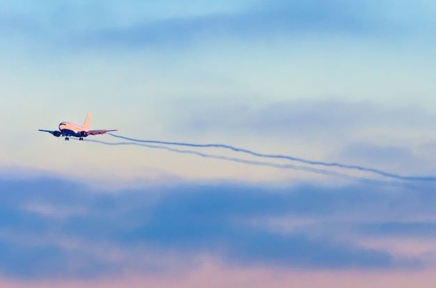 Das Flugzeug kommt am Flughafen an, bevor es bei Sonnenuntergang durch die Wolken landet.