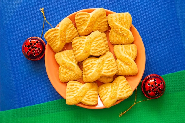 Foto das foto eines haufens von keksen oder shortcake-keksen auf dem teller mit roten glocken. hintergrund des nationalen cookie-tages. weihnachtsfrühstück für den weihnachtsmann.