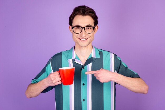 Das Foto eines jungen, fröhlichen Mannes zeigt die morgendliche Cappuccino-Koffein-Werbung der Fingertasse, die über violettem Farbhintergrund isoliert ist