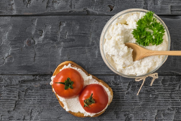 Das Frühstück besteht aus geröstetem Brot, Hüttenkäse und Tomaten auf einem Holztisch.