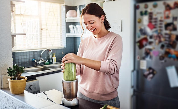 Das Frühstück ist gemischt und trinkfertig. Schnappschuss einer jungen Frau, die zu Hause in der Küche einen Smoothie zubereitet