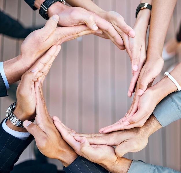 Das Geschäft funktioniert nur, wenn wir eine Hochwinkelaufnahme einer Gruppe nicht erkennbarer Geschäftsleute machen, die mit ihren Händen bei der Arbeit einen Kreis bilden