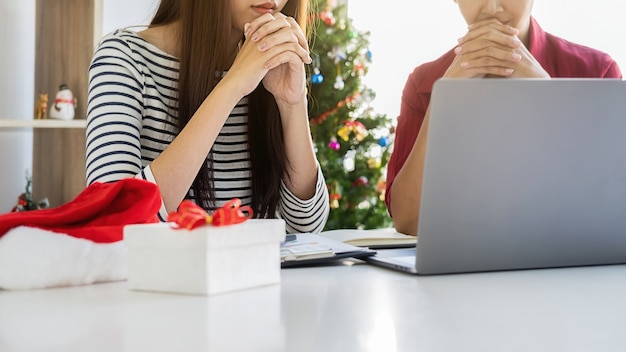 Das Geschäftsteam diskutiert Finanzdaten und Berichtsdiagramme am letzten Arbeitstag. Junge kreative Leute feiern Urlaub im modernen Büro. Frohe Weihnachten und ein glückliches Neues Jahr.