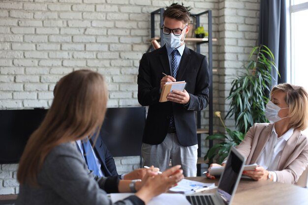 Das Geschäftsteam in Schutzmasken arbeitet im Büro.