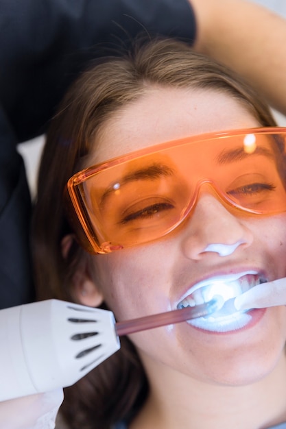 Foto das gesicht des weiblichen patienten, das laser-zähne durchmacht, die behandlung weiß werden