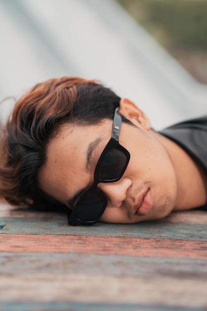 Das Gesicht eines sehr dummen Asiaten mit Sonnenbrille auf dem Kopf beim Entspannen in einem Café