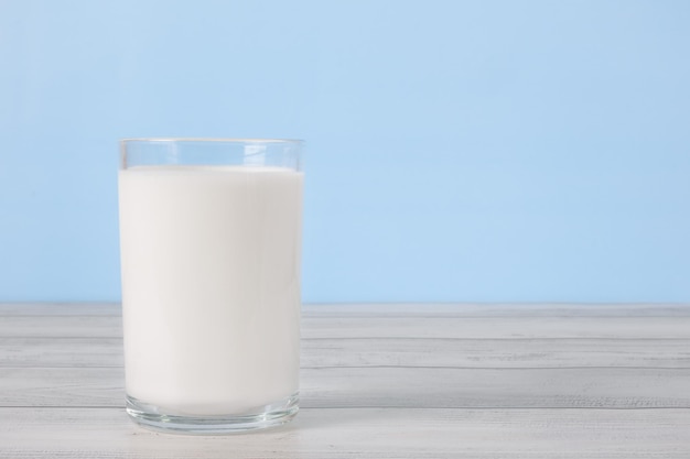 Das Glas voll Milch auf Holztisch Glas frische weiße Milch auf blauem Hintergrund